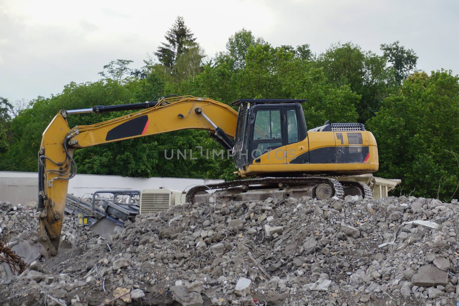 Yellow excavator at demolition on mountain of debris, view from by MarkDw