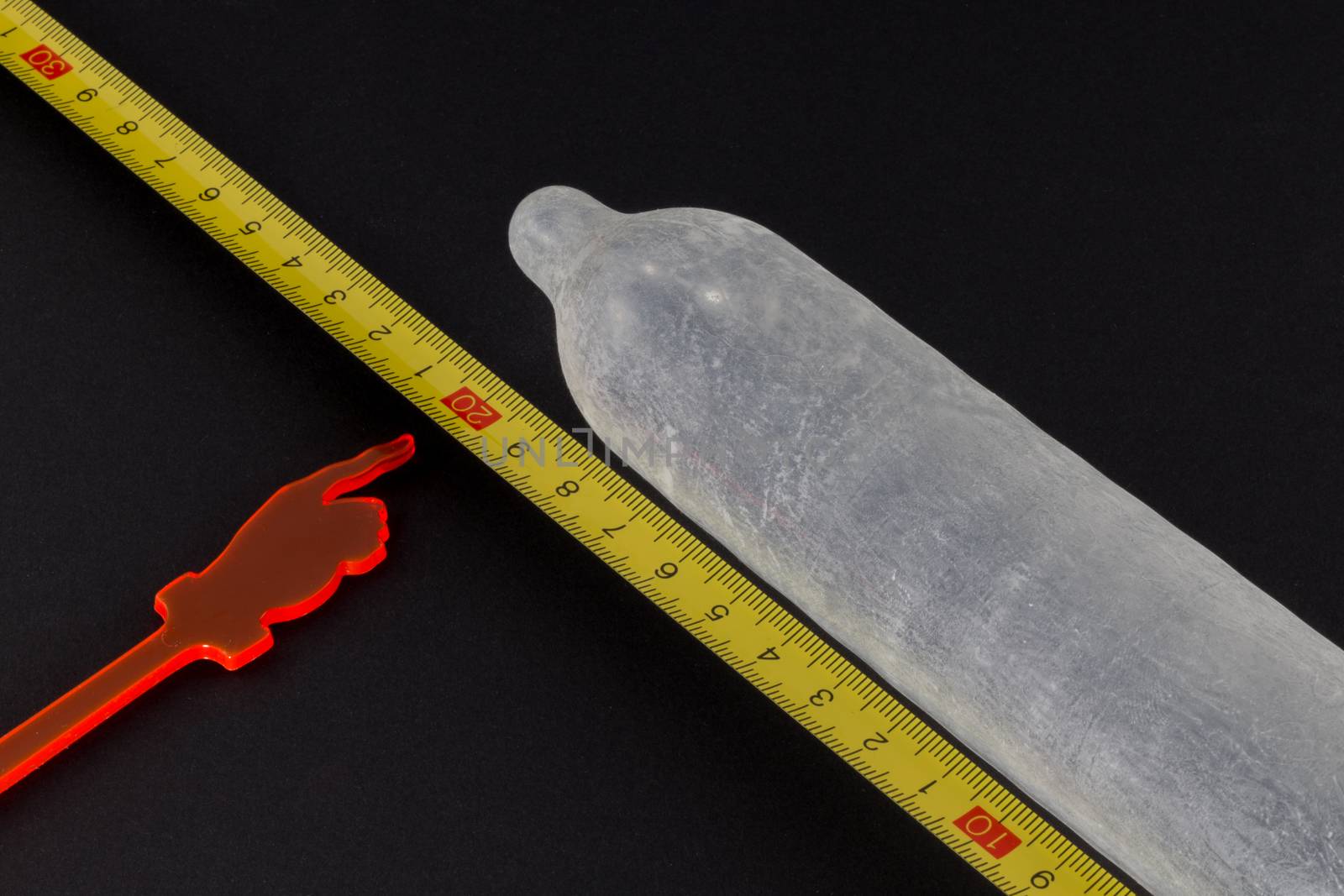 Inflated condom next to measuring tape, pointer to twenty centimeters mark
