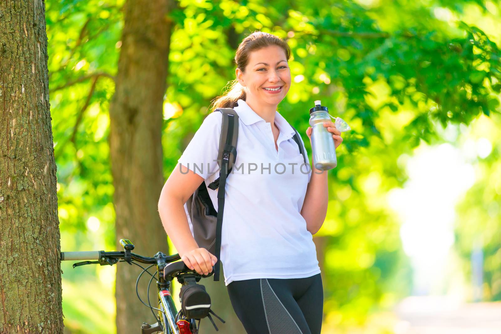 Happy sportswoman with a bottle of water and a bicycle by kosmsos111