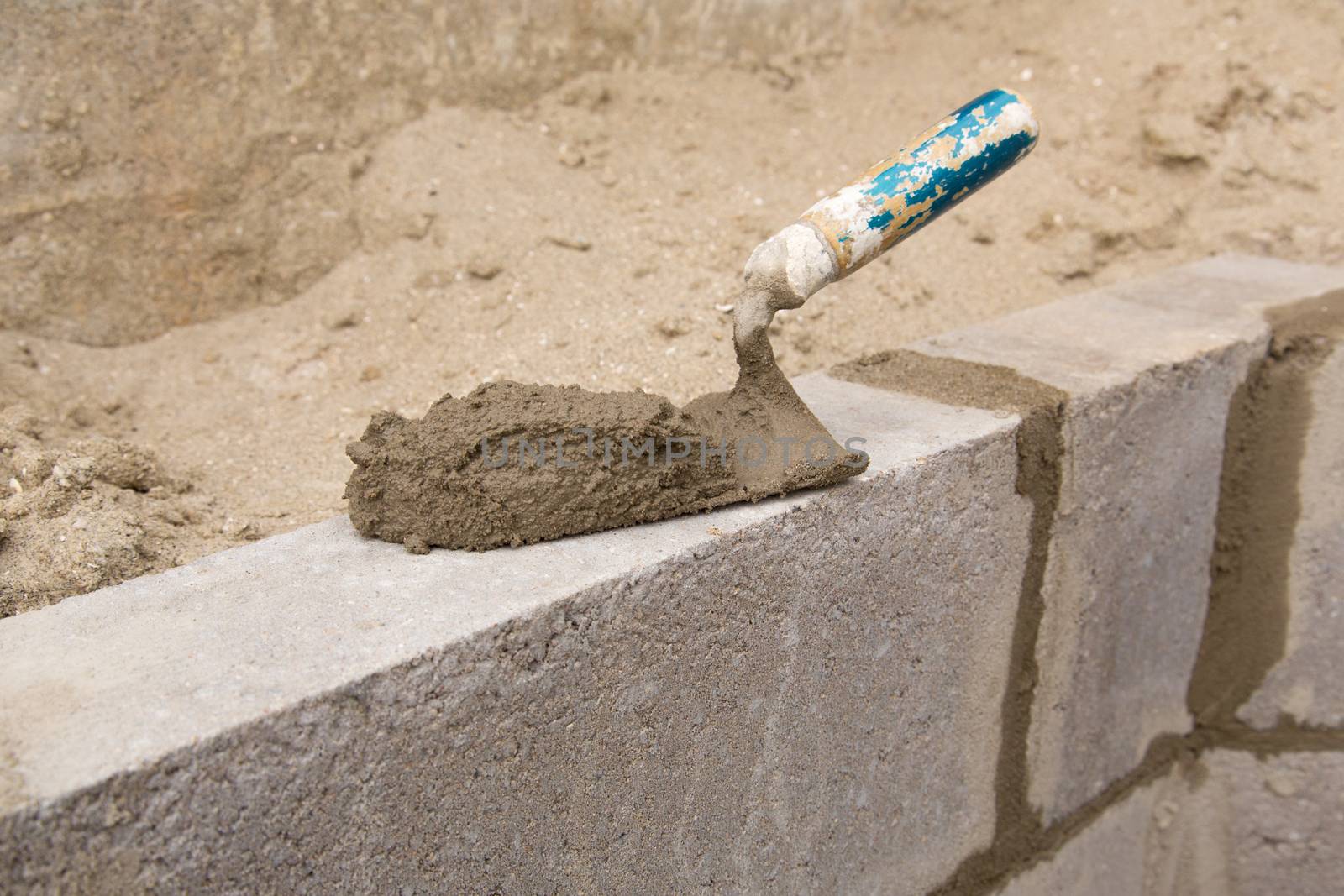 Trowel with concrete on a constructed wall outdoors