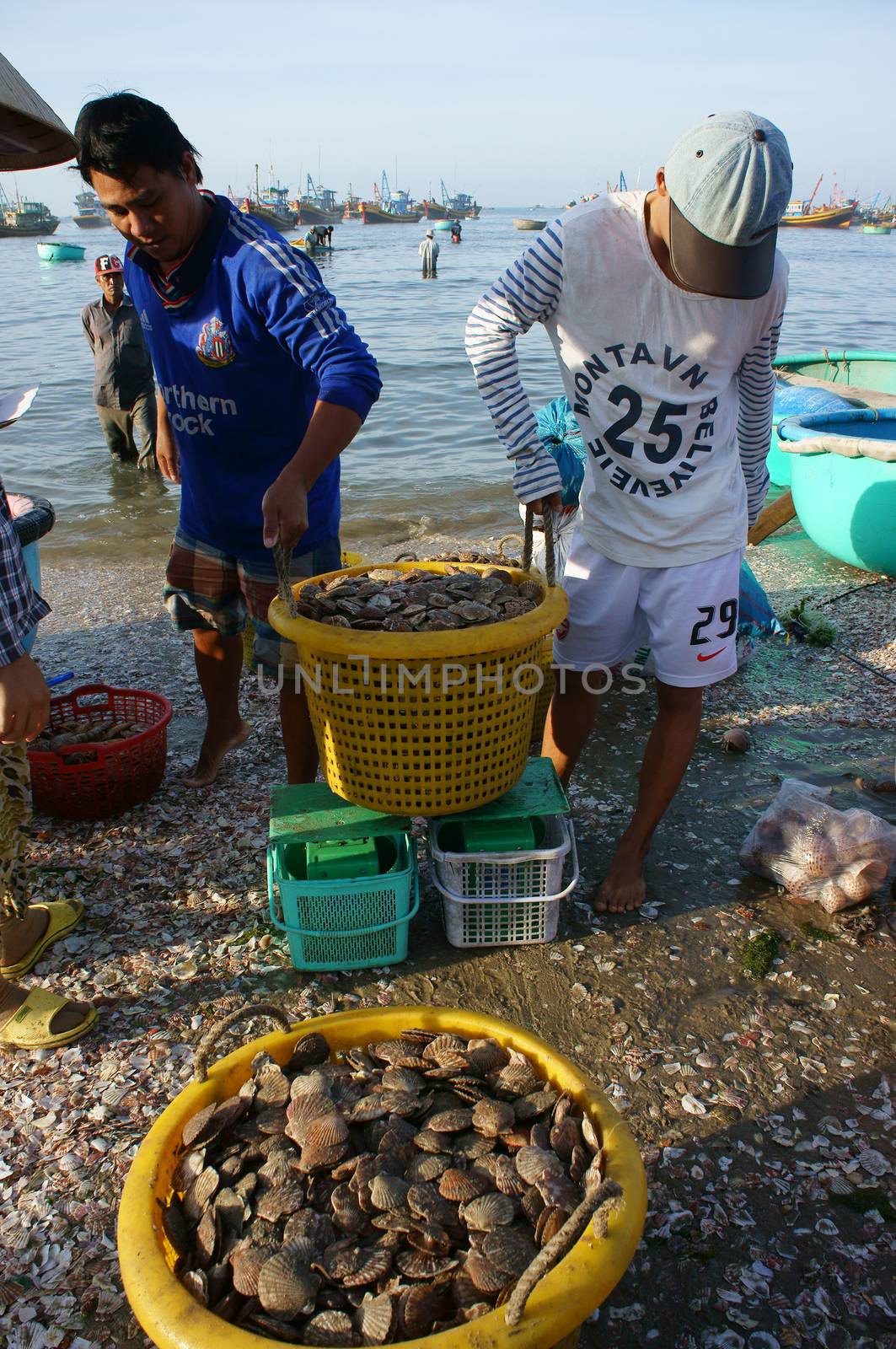 PHAN THIET- VIETNAM- JAN 21:  Seafood market on beach, people trader fishing product in morning, boat on water,  person carry fresh food, Viet Nam, Jan 21, 2014