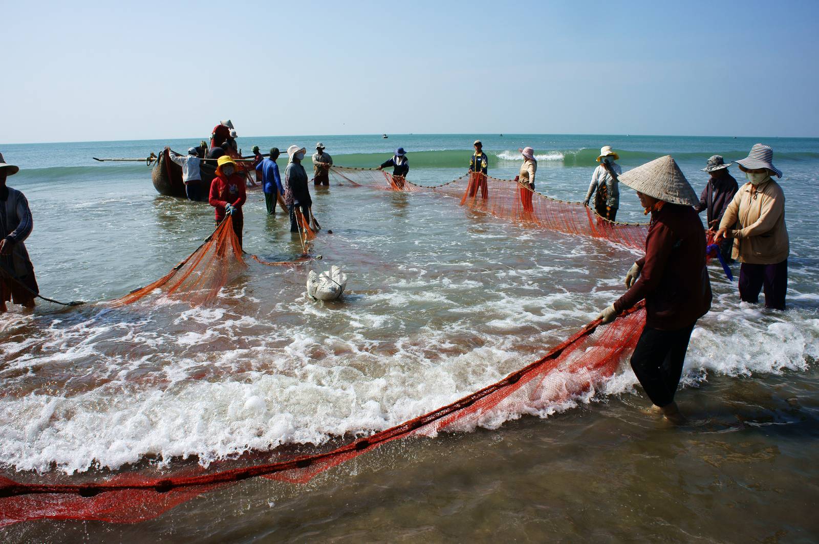 BINH THUAN, VIETNAM- JAN 22: Team work of fisherman on beach, group of people pull fishing net to catch fish, stand in row, person move to seashore, crowded atmosphere, fresh air,Viet Nam, Jan22, 2014