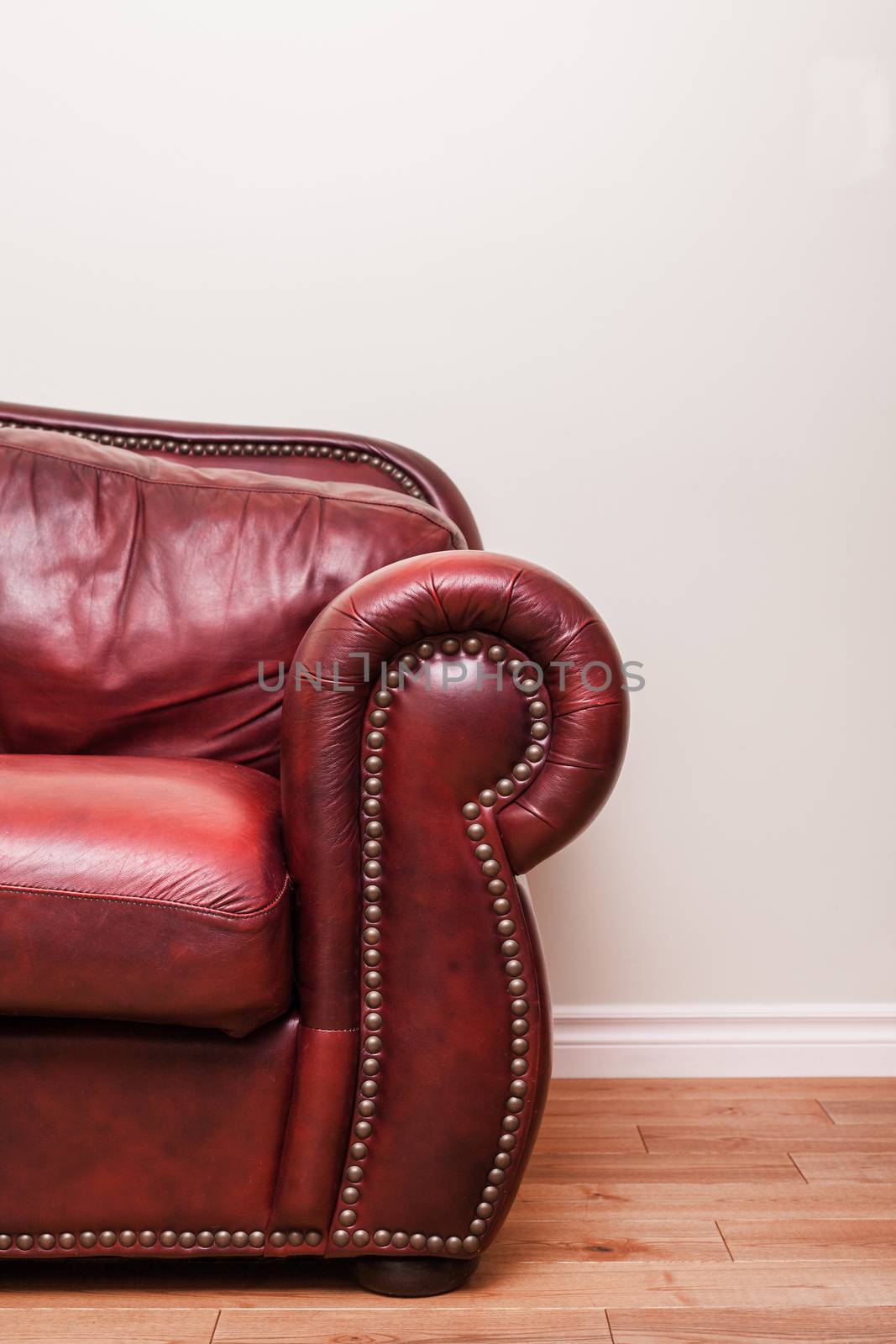 Luxurious Red Leather Couch Detail in front of a blank wall to ad your text, logo, images, etc.