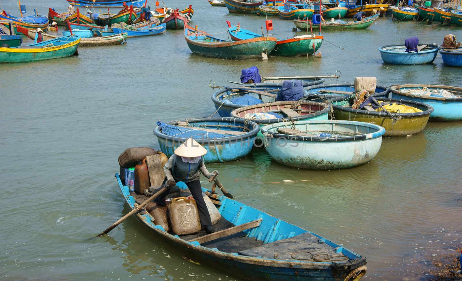 BINH THUAN, VIETNAM- JAN 20: Transportation people and goods by small wooden boat from fishing boat to shore, colorful fishing boat on habor on day at fishing village, Viet Nam, Jan 20, 2014