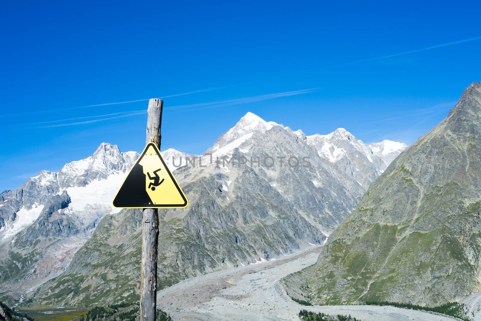 COMBAL, ITALY, AUGUST 28: Slippage danger sign with Miage Glacier and Combal peaks in the background. The area is on a stage of the popular European Mont Blanc tour. August 28, 2014 in Combal.