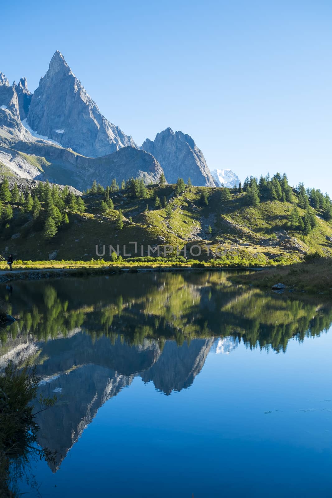 Combal Needles reflected on Combal Lake water on a sunny day in Val Veny, in Italy.