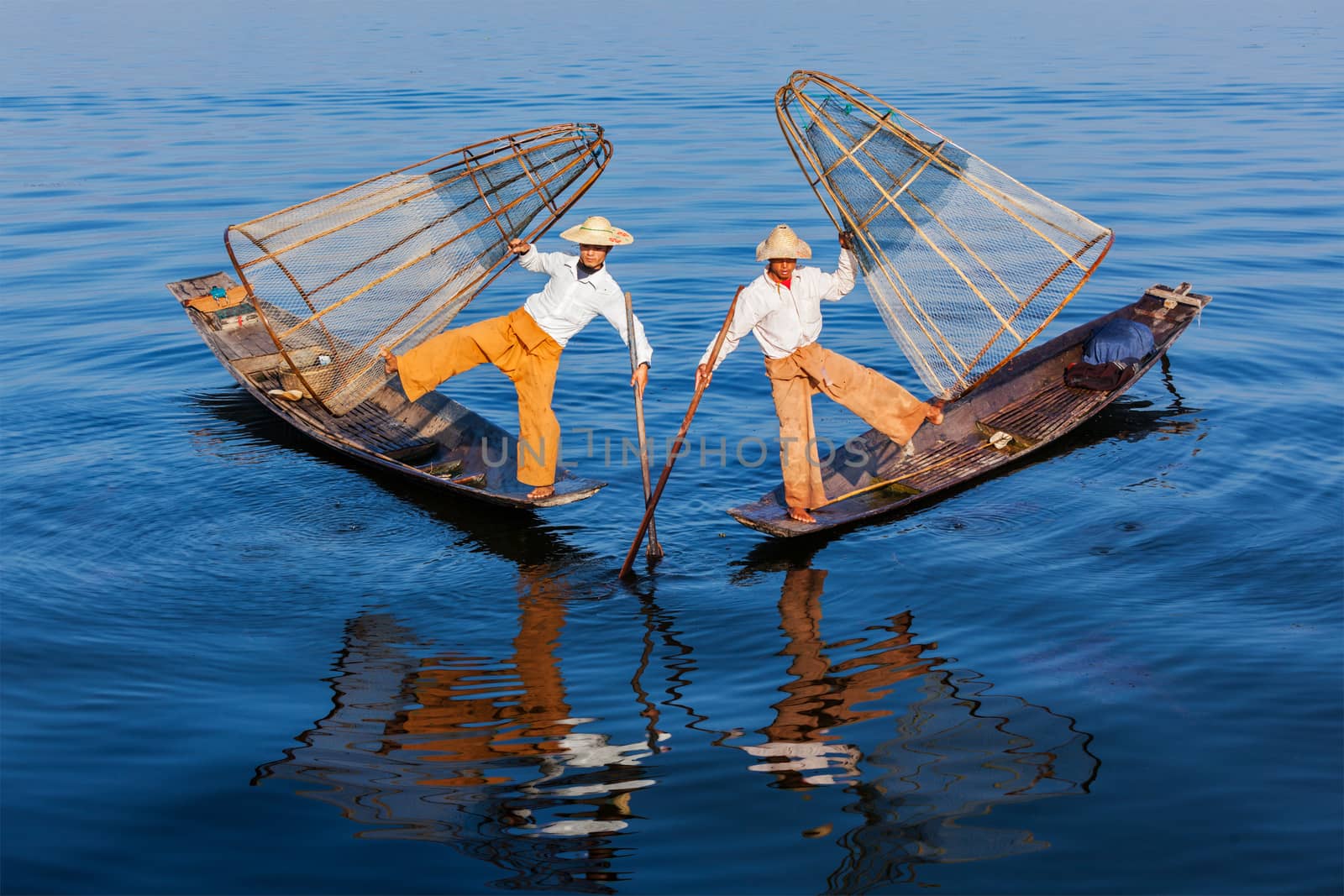 Myanmar travel attraction landmark - Traditional Burmese fishermen balancing with fishing net at Inle lake in Myanmar famous for their distinctive one legged rowing style