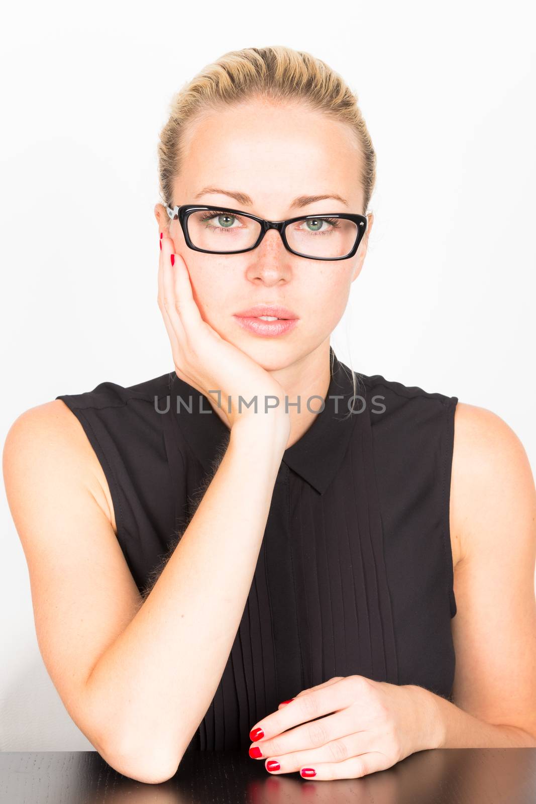 Business woman wearing black glasses sitting at the table resting her head on his hand.