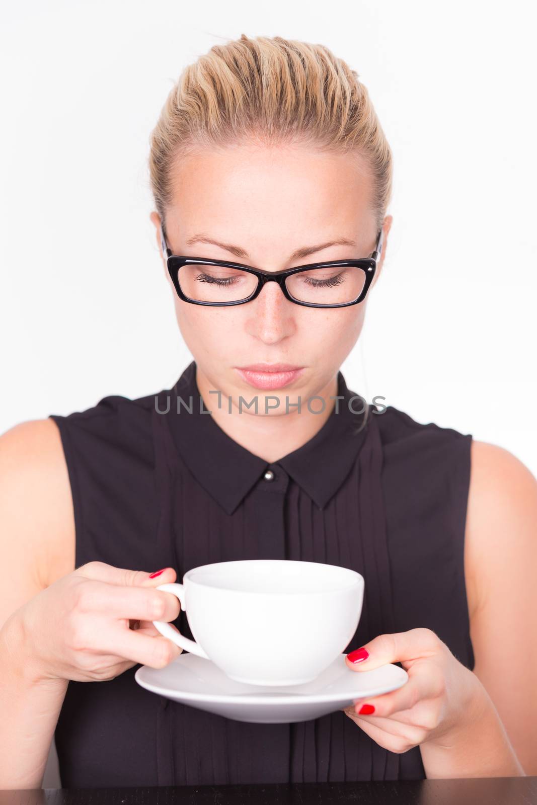 Business woman wearing black glasses holding white cup of coffee in her hands. Coffee break.