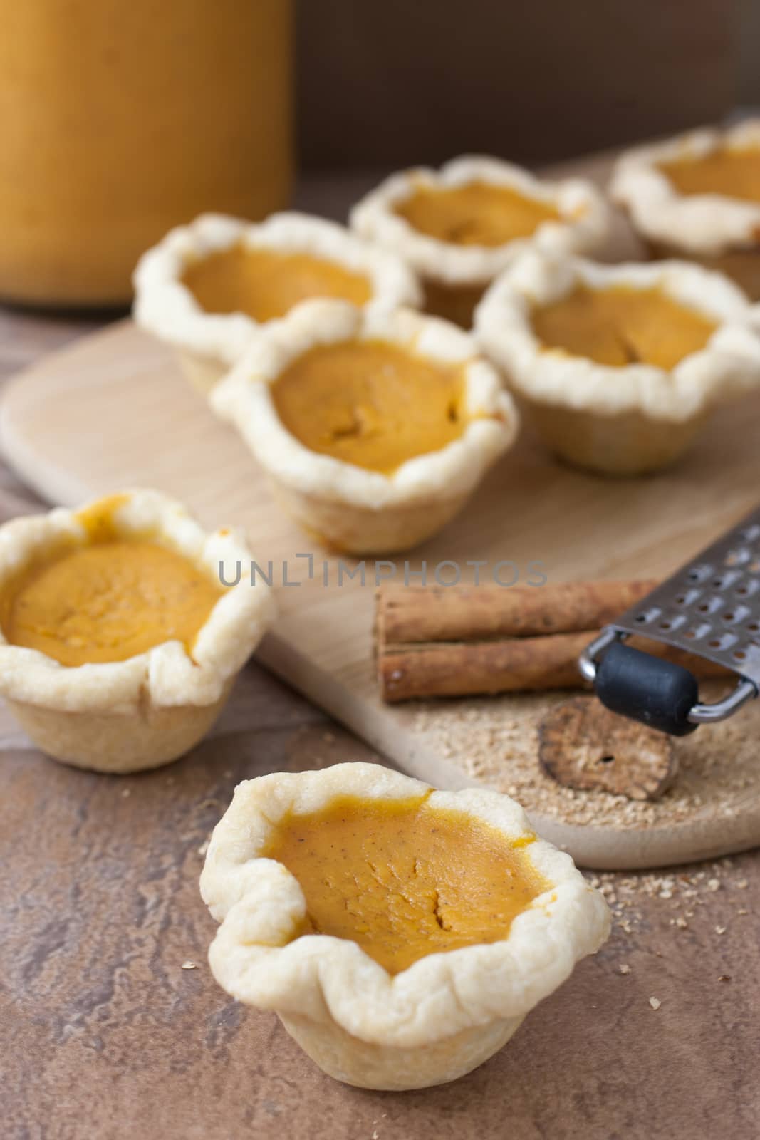 Mini or bite-sized pumpkin pies lined up on a counter top.