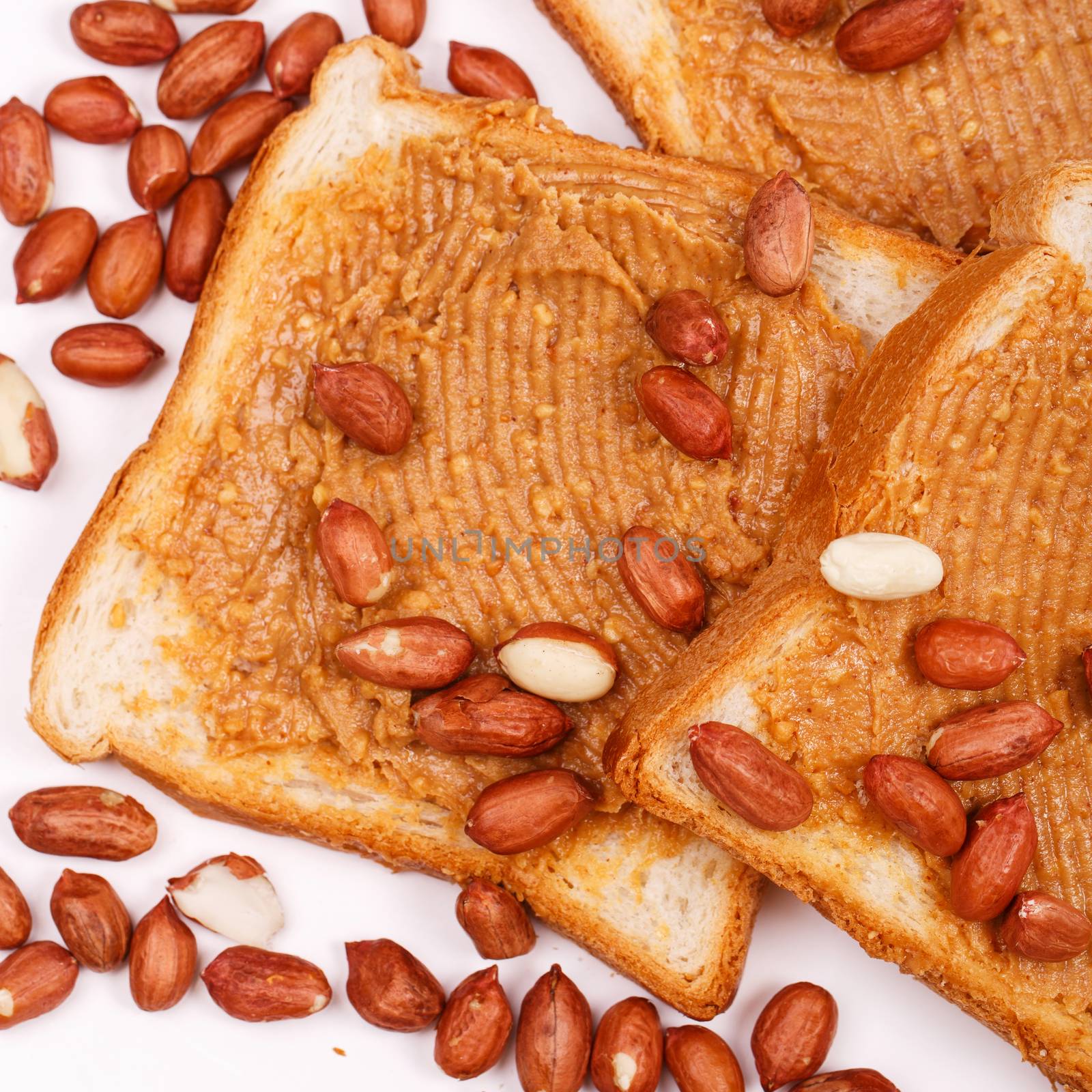 Peanut butter sandwich with heap of peanuts on the table