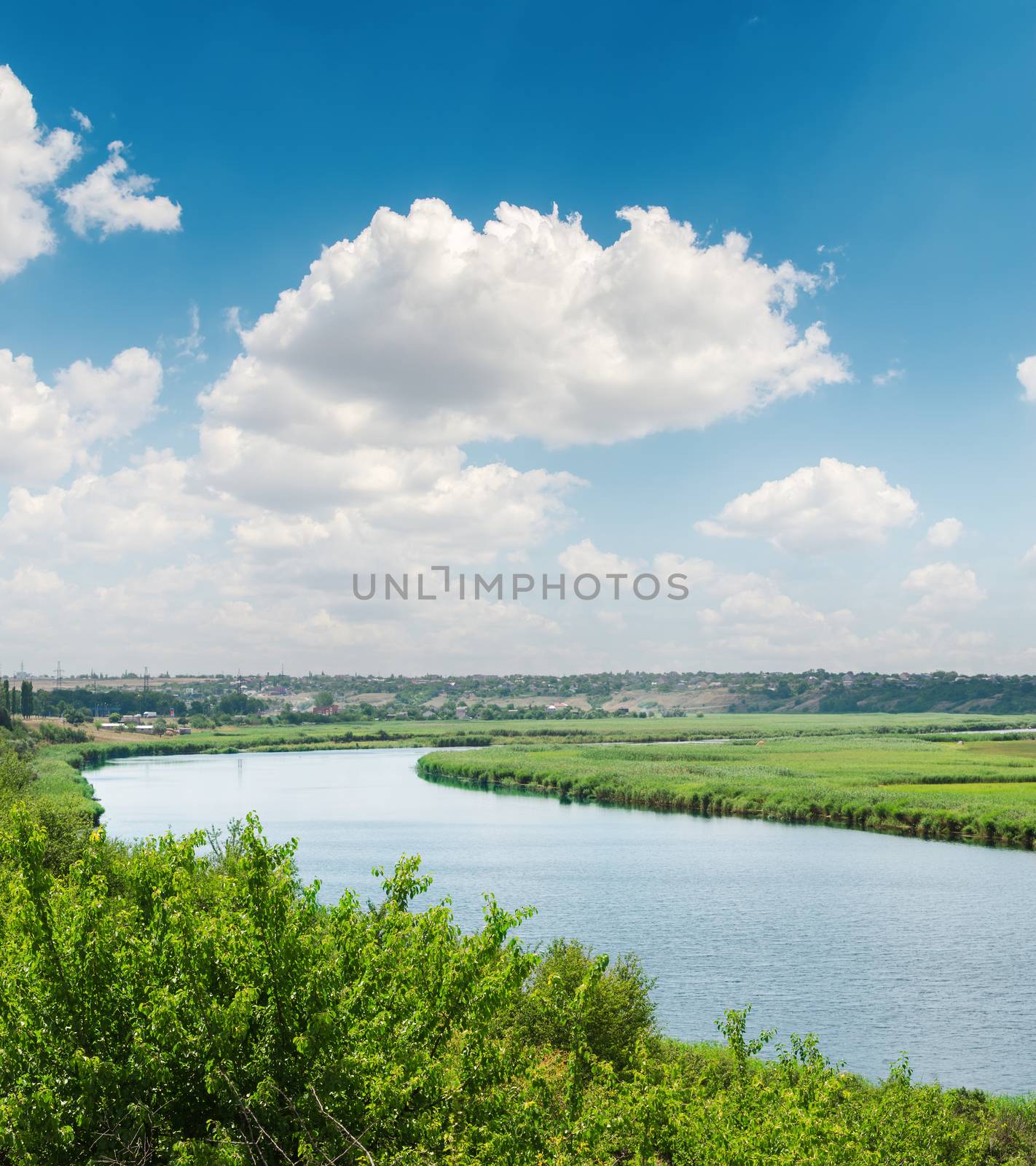 blue sky with white clouds over river in green riverside by mycola