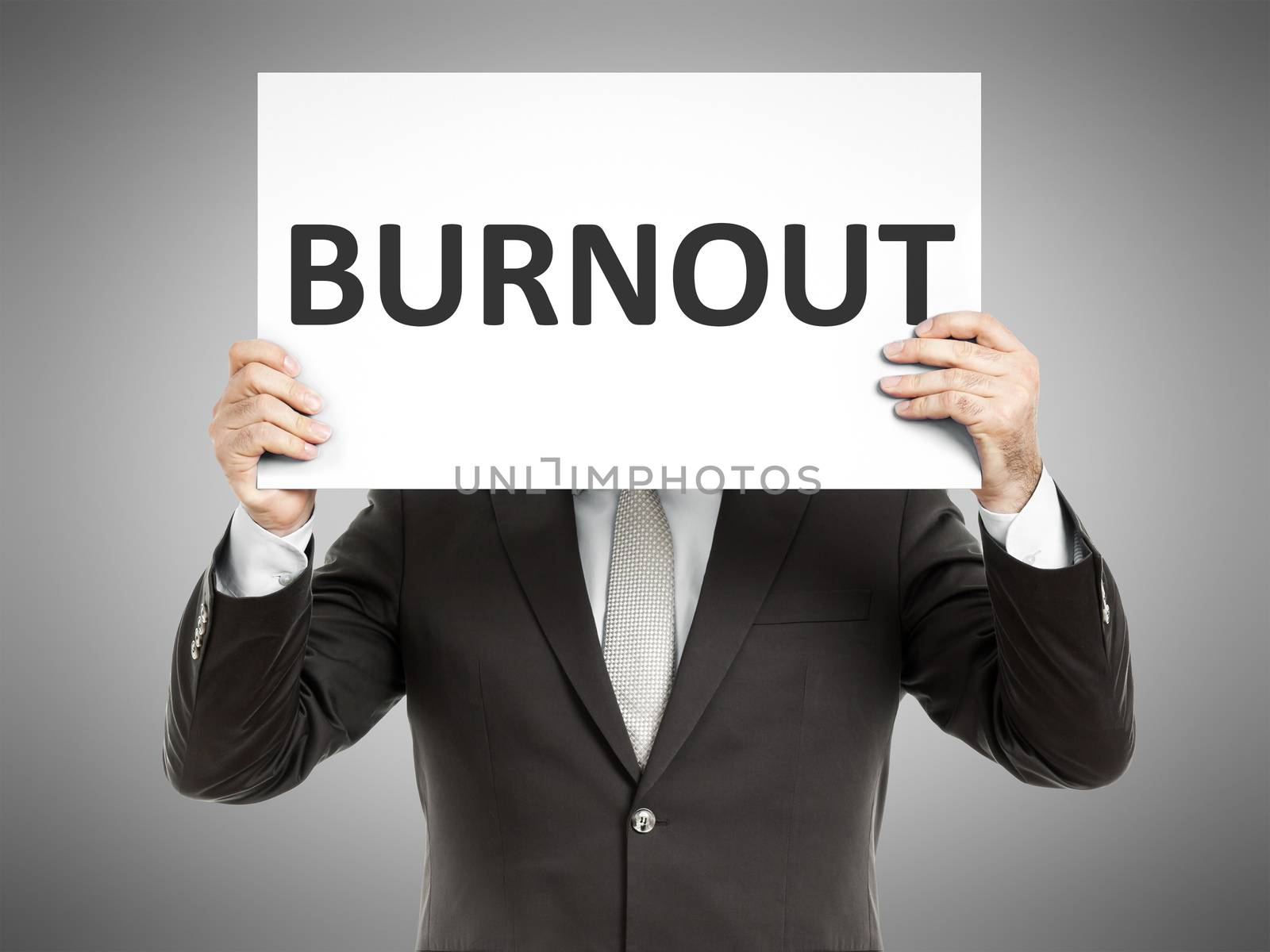 A business man holding a paper in front of his face with the text burnout