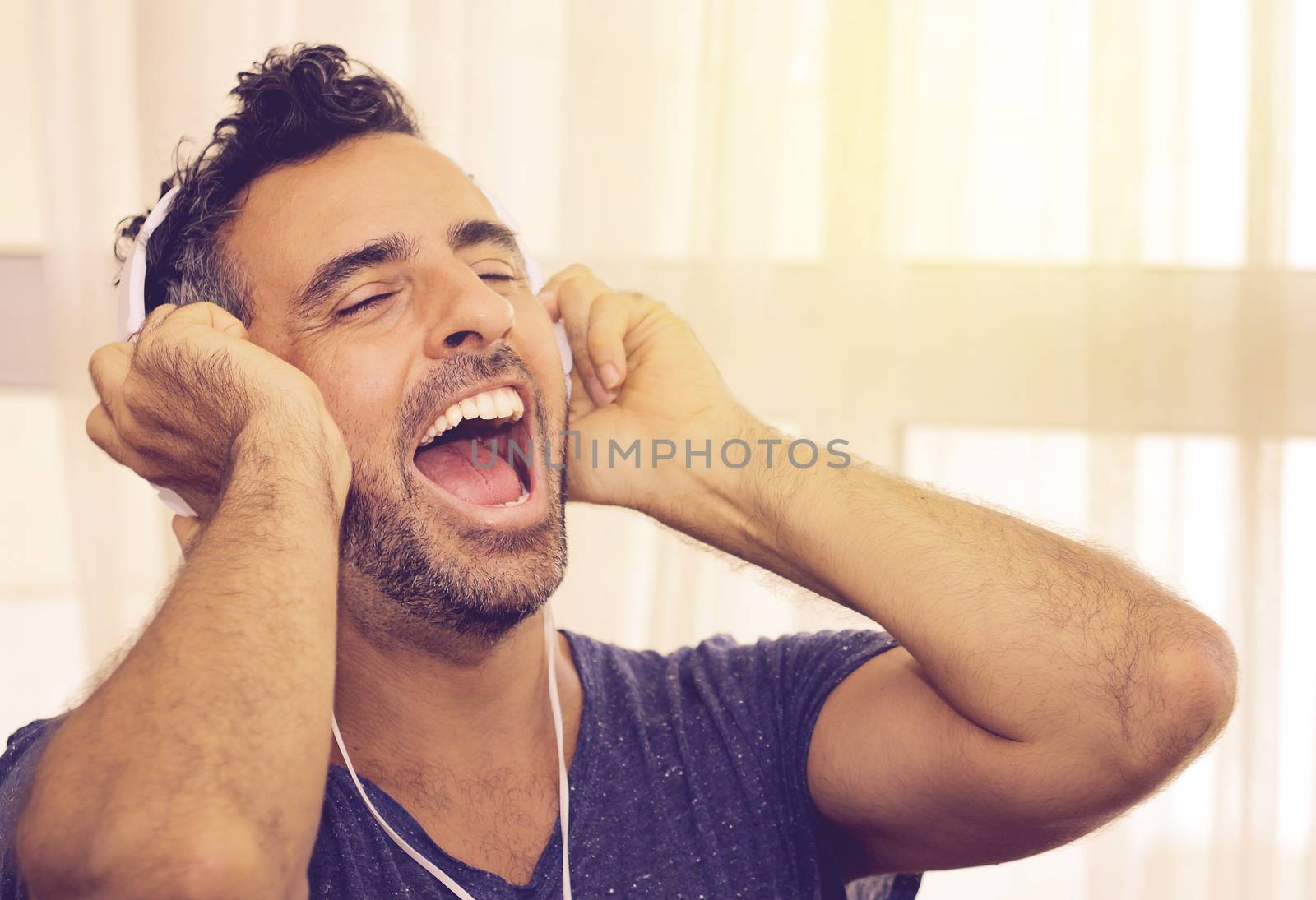 Exuberant handsome young man listening to his music cheering and singing along to the lyric and beat as he listens to the soundtrack on his headphones