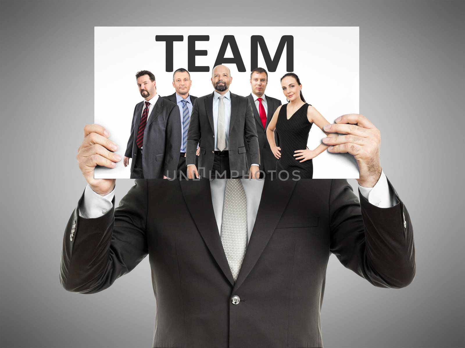 A business man holding a paper in front of his face with a team