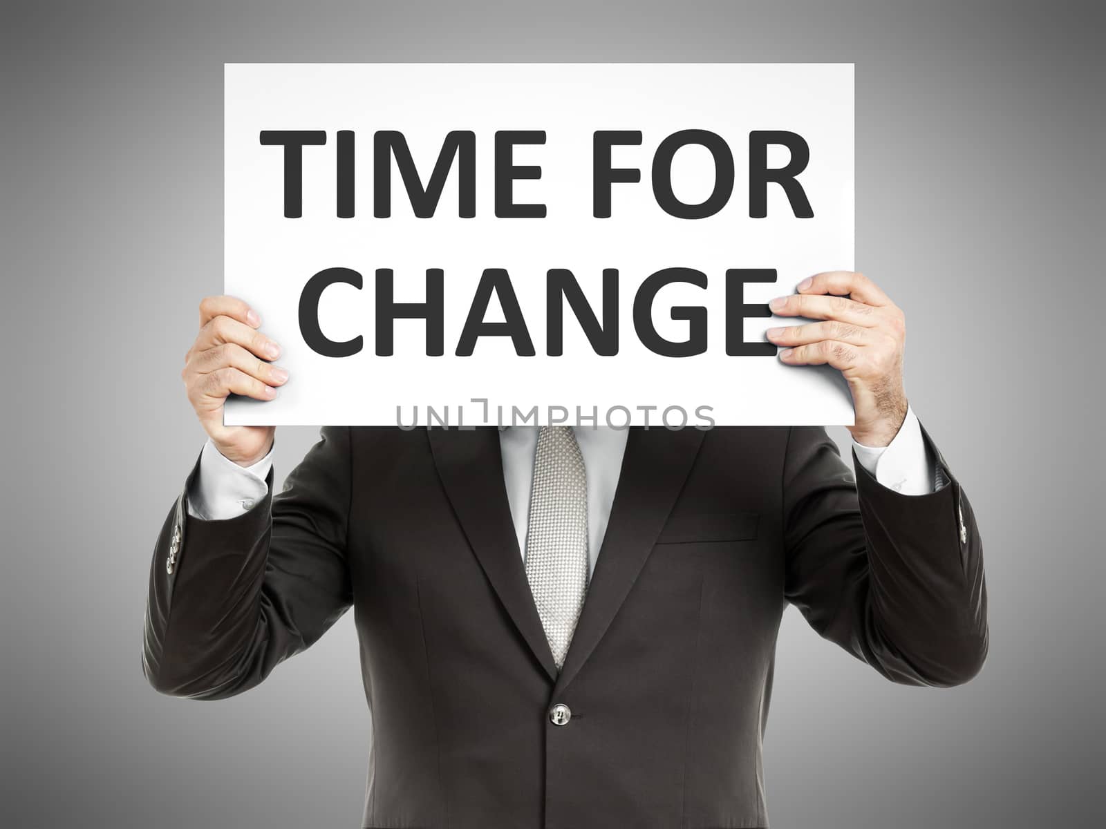 A business man holding a paper in front of his face with the text time for change