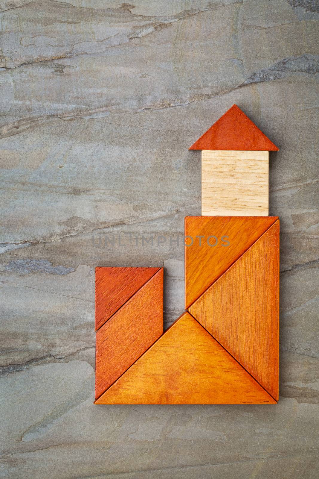 abstract lighthouse, house with a tower or church built from seven tangram wooden pieces, a traditional Chinese puzzle game, slate rock background, artwork created by the photographer