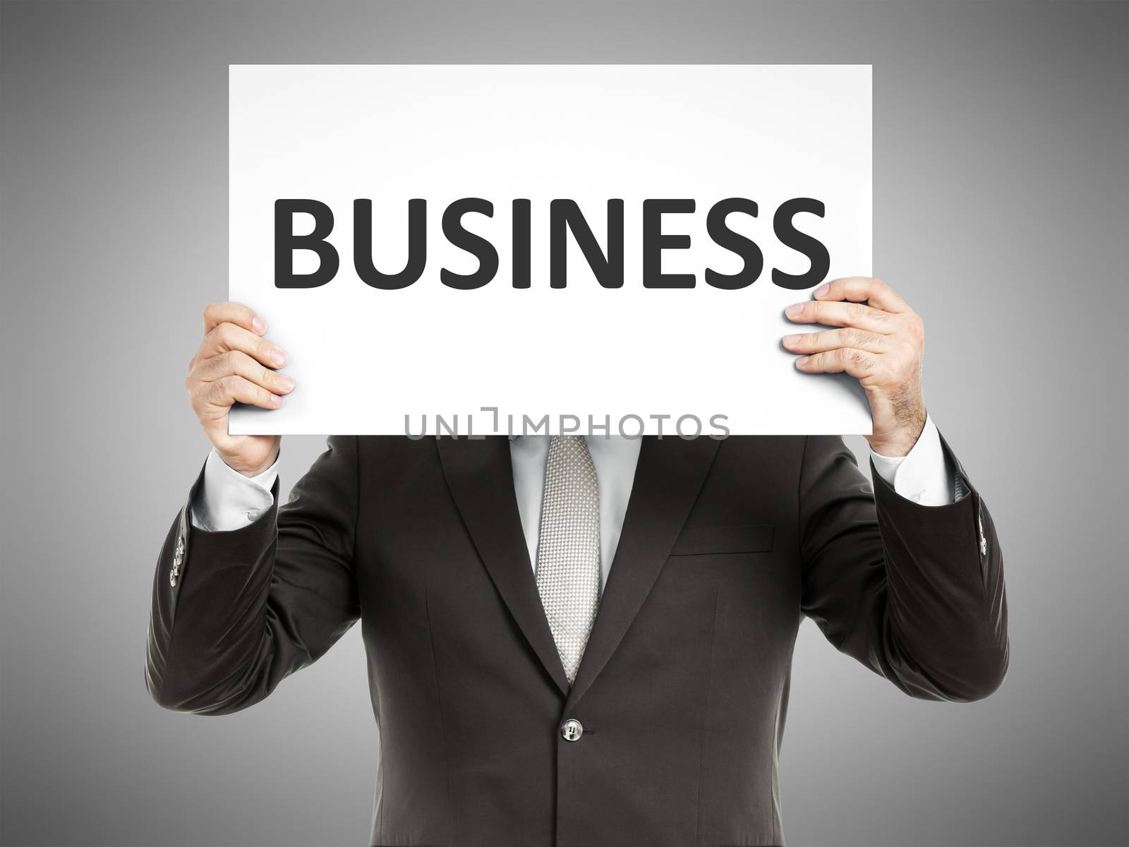 A business man holding a paper in front of his face with the word business