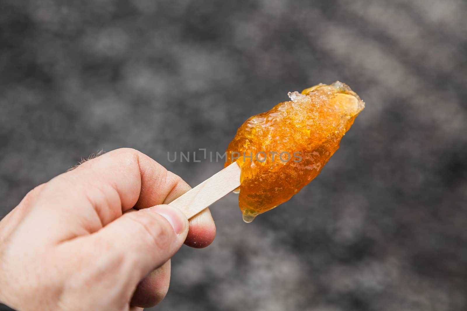 Hand Holding Maple Taffy on a wood stick