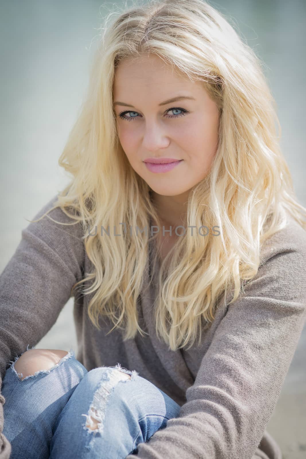 Blond woman sitting at lake by w20er