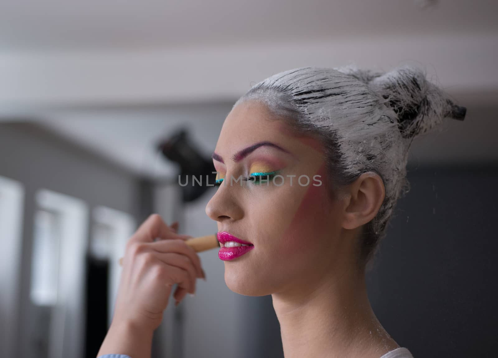 Model applying make up and preparing for photoshoot