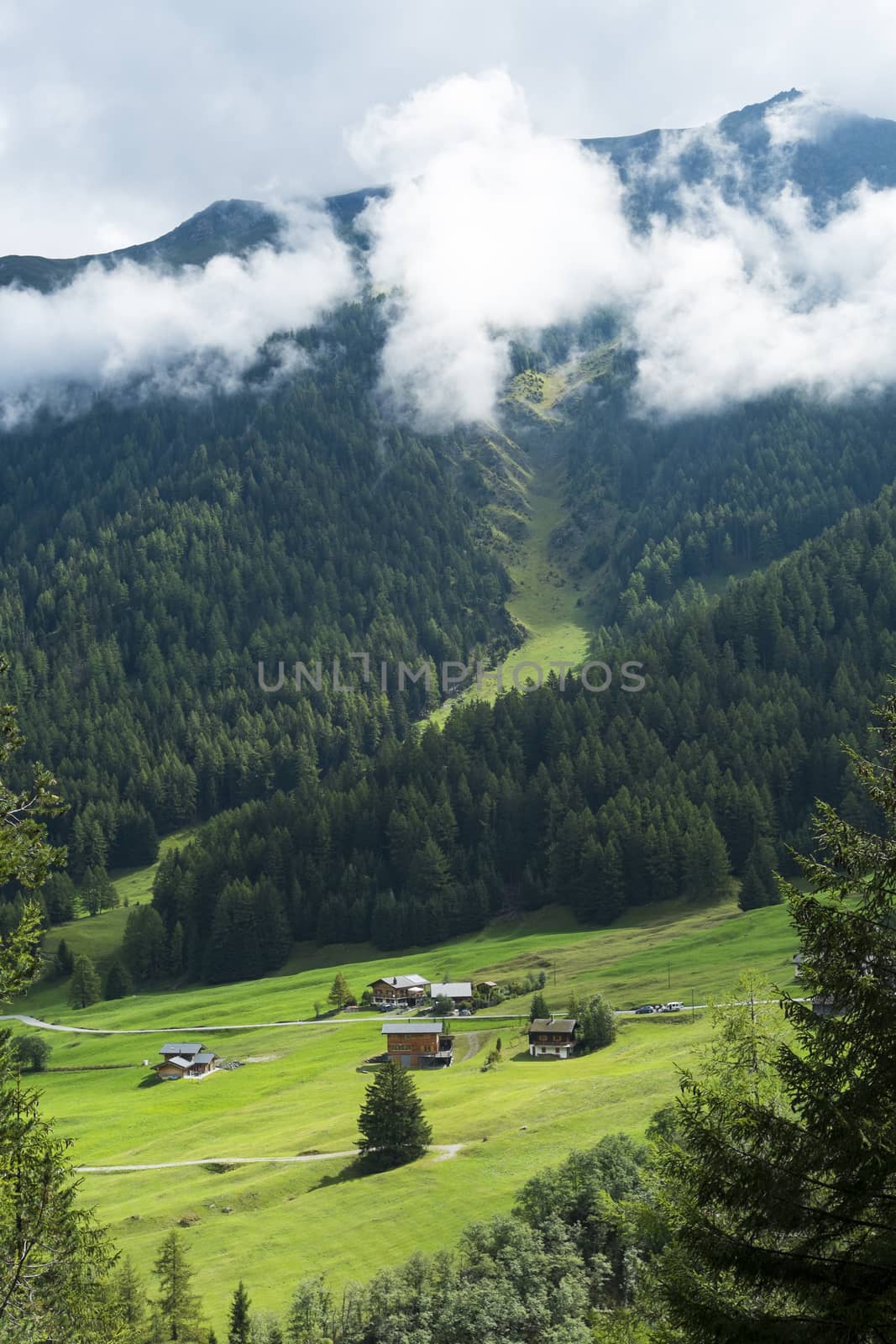 PRAYON, SWITZERLAND - AUGUST 30: Small village at the bottom of forest on hill, with low hanging clouds. The area is a stage of the popular Mont Blanc tour. August 30, 2014 in Prayon.