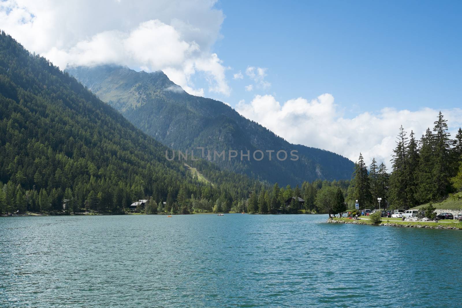 CHAMPEX, SWITZERLAND - AUGUST 30: Placid lake with tree covered mountains in the background. The village is one of the Mont Blanc tour stages. August 30, 2014 in Champex.