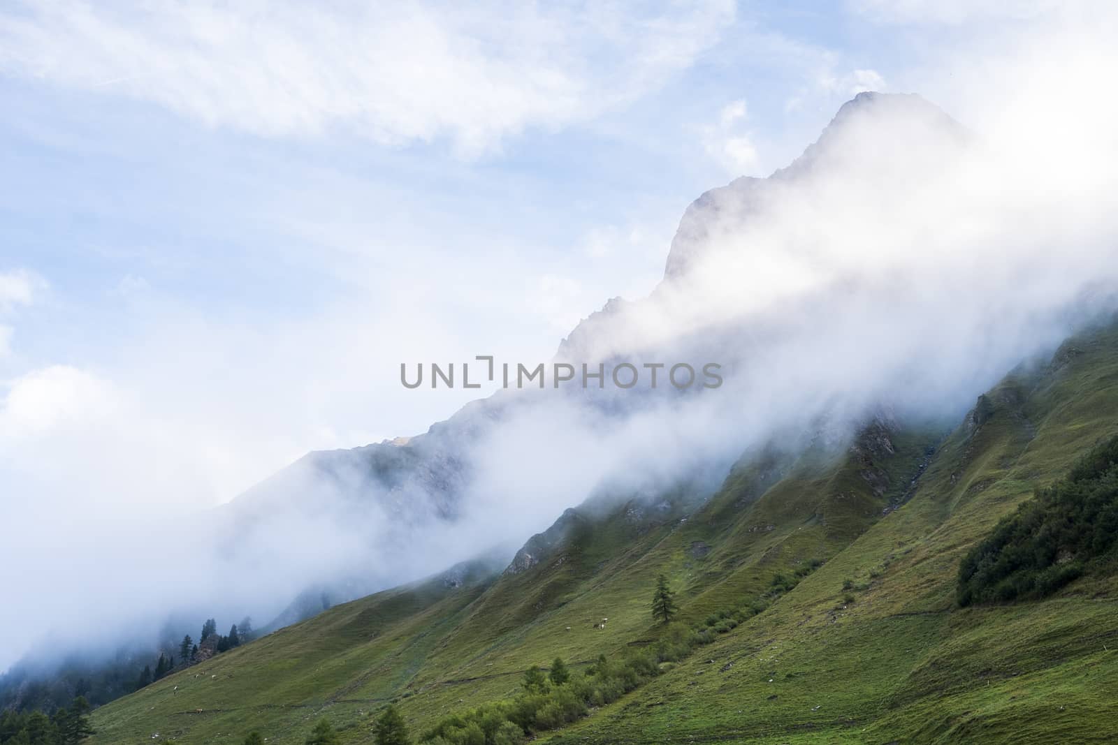Clouds rolling down hillside in les Ars Dessus, Switzerland. The region is one of the stages in the popular Mont Blanc tour, which crosses France, Italy and Switzerland.