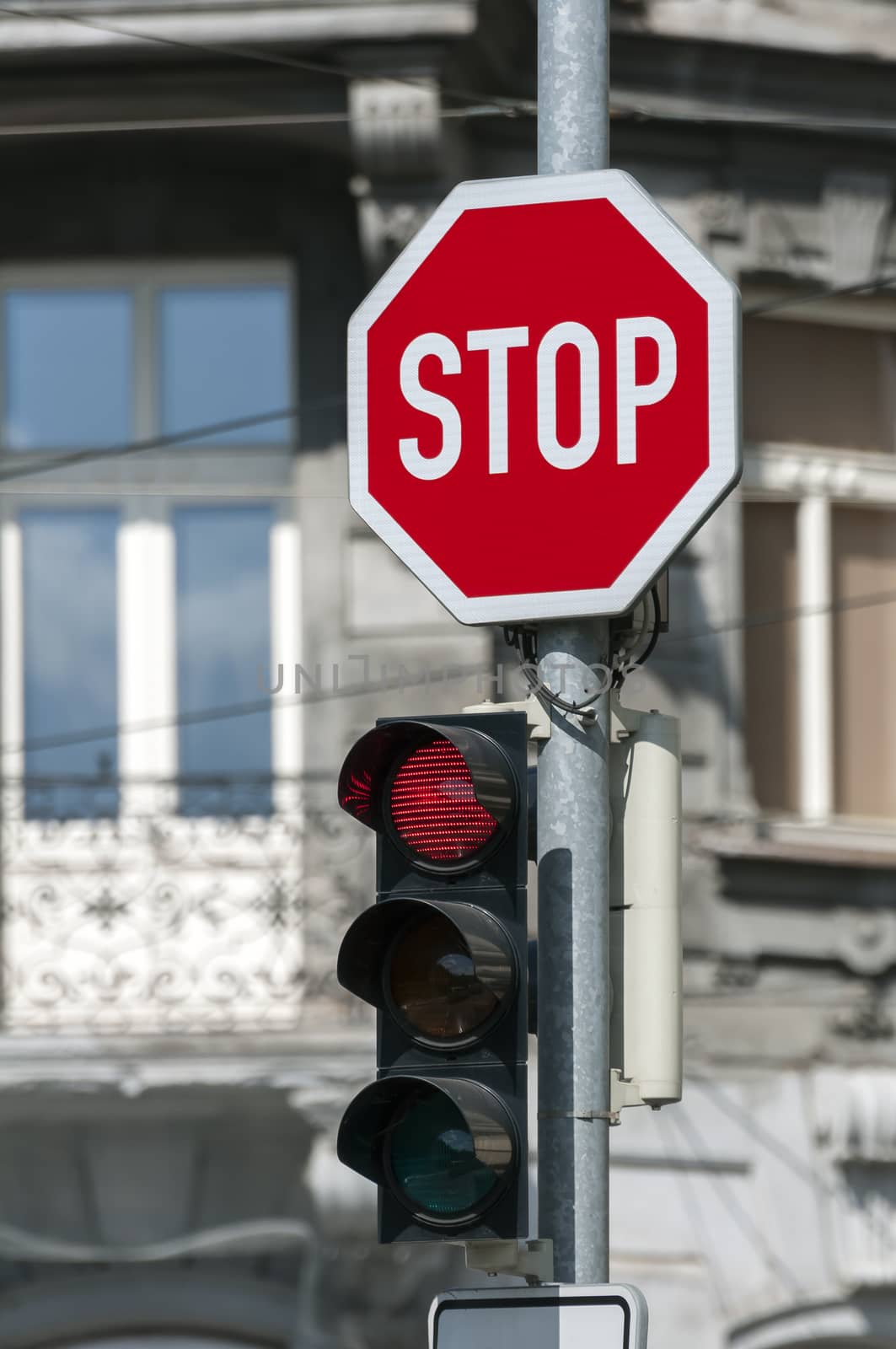 Red traffic light on and stop sign.