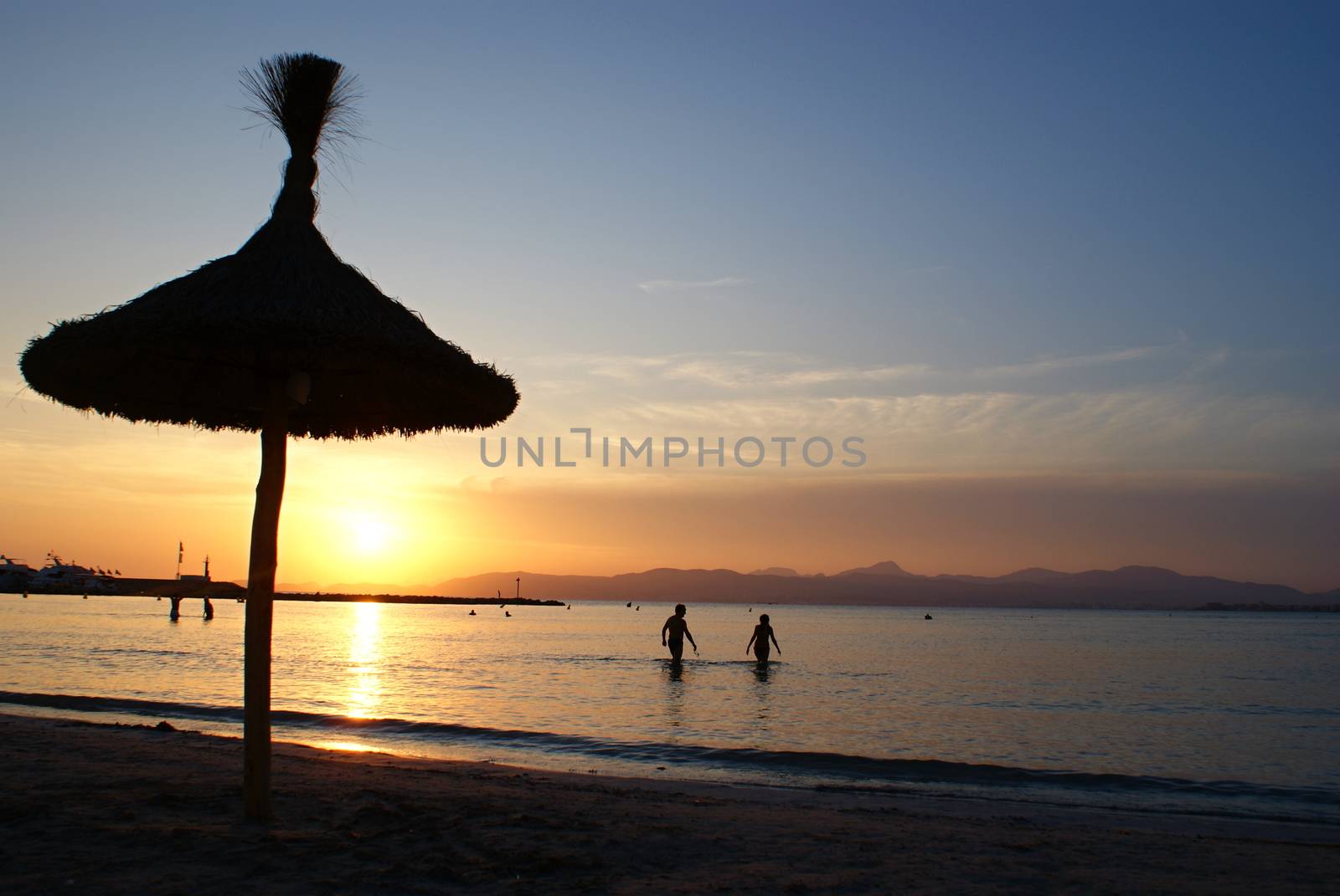 Photo is showing sunset above the beach and sea of Mallorca, Spain.