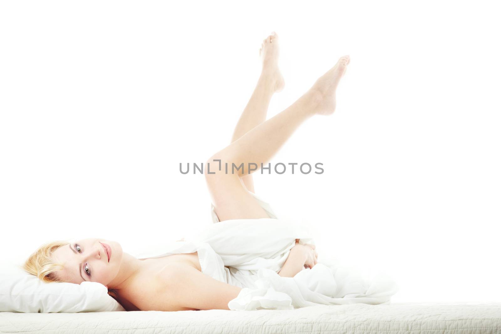Smiling lady laying on the bed on a white background. Horizontal photo