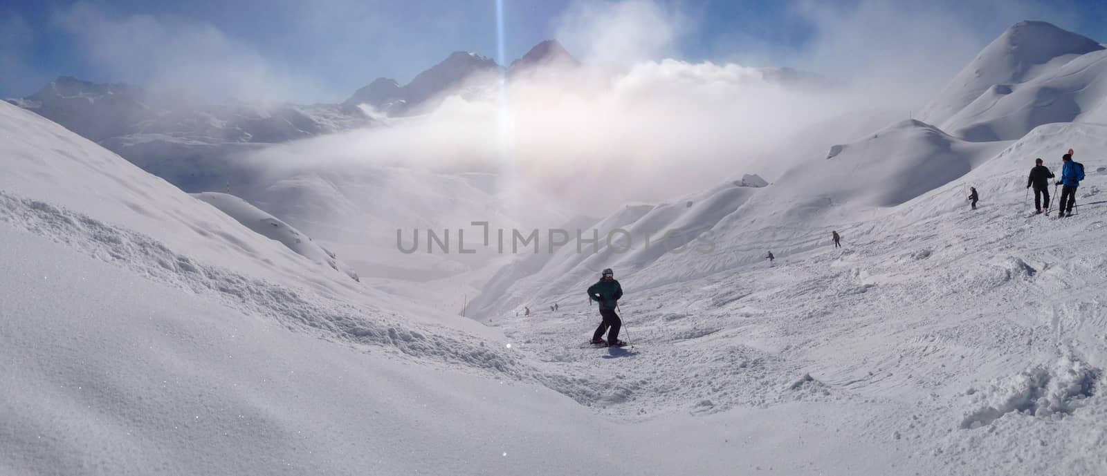 A skier on the piste in front of beautiful mountains