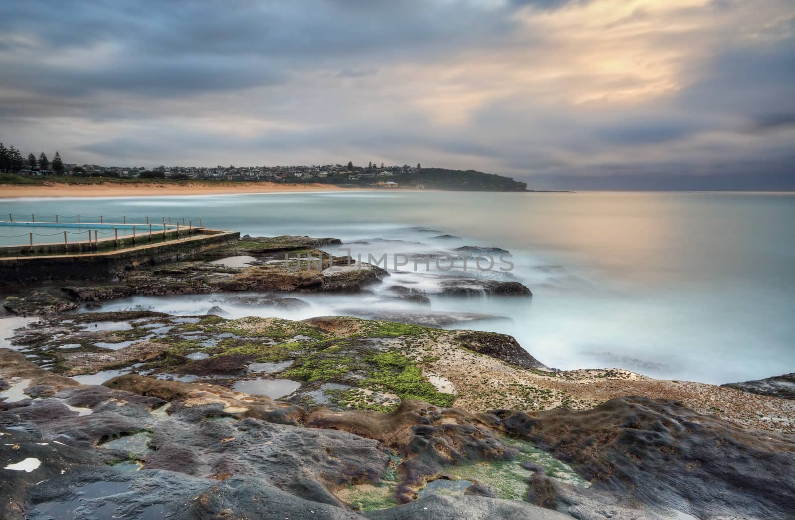 North view overlooking coast and rock pool at South Curl Curl. Australia.  Motion in water, clouds and railings