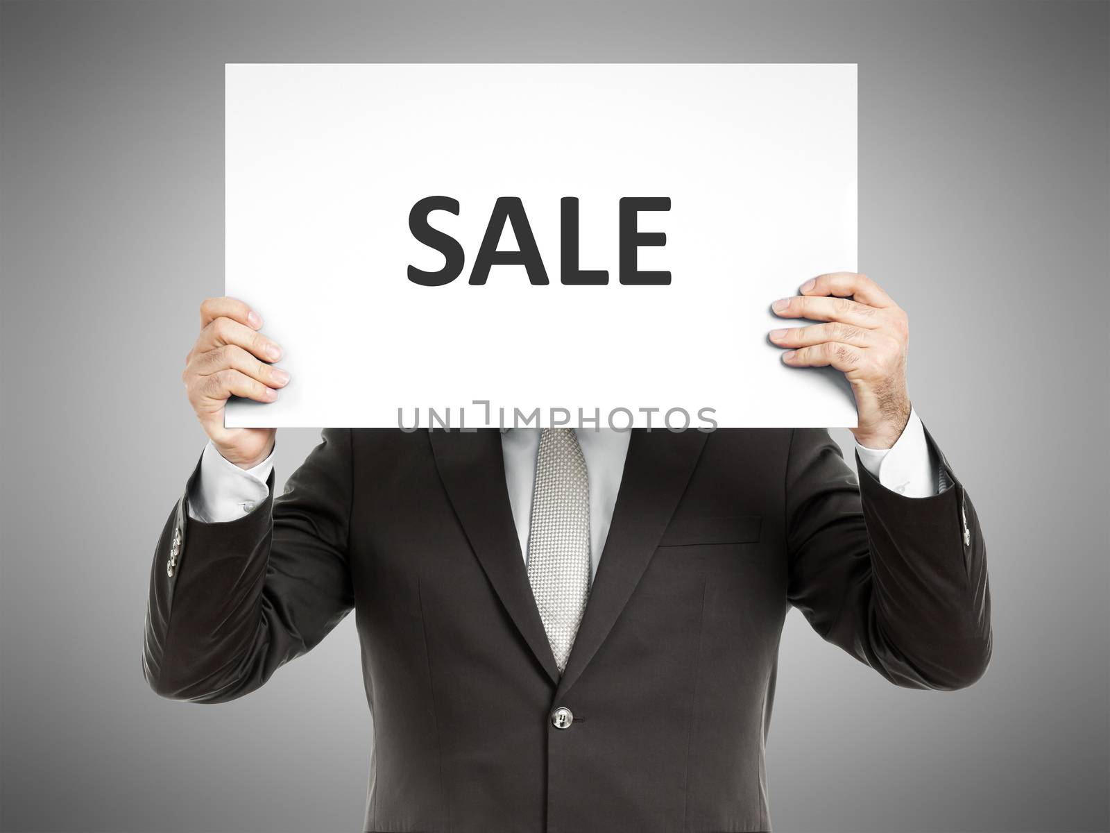 A business man holding a paper in front of his face with the text sale