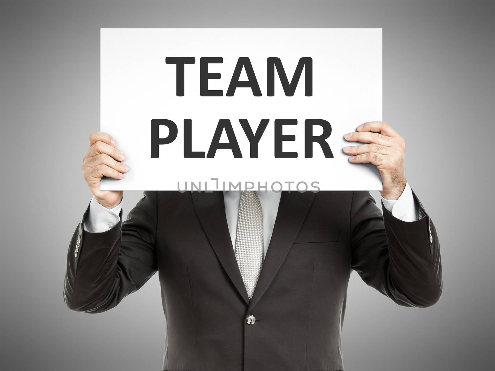 A business man holding a paper in front of his face with the text team player