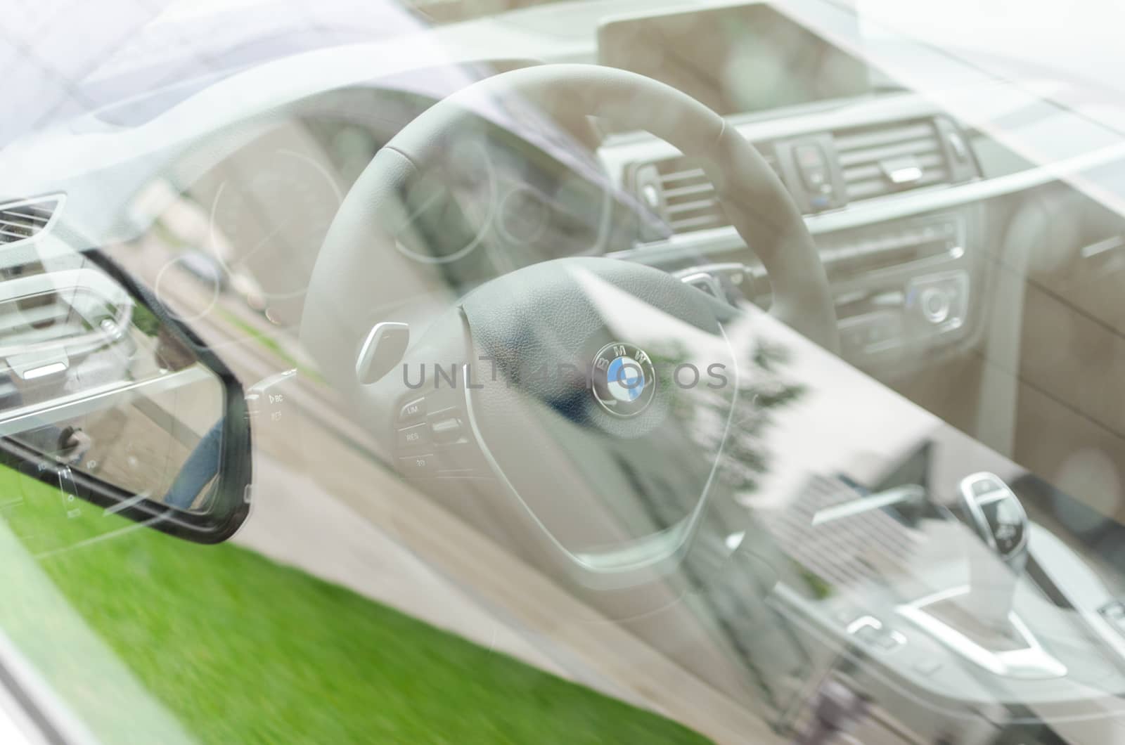 MUNICH, GERMANY - AUGUST 9, 2014: Interior of new modern model BMW car through the side window glass with grass reflection