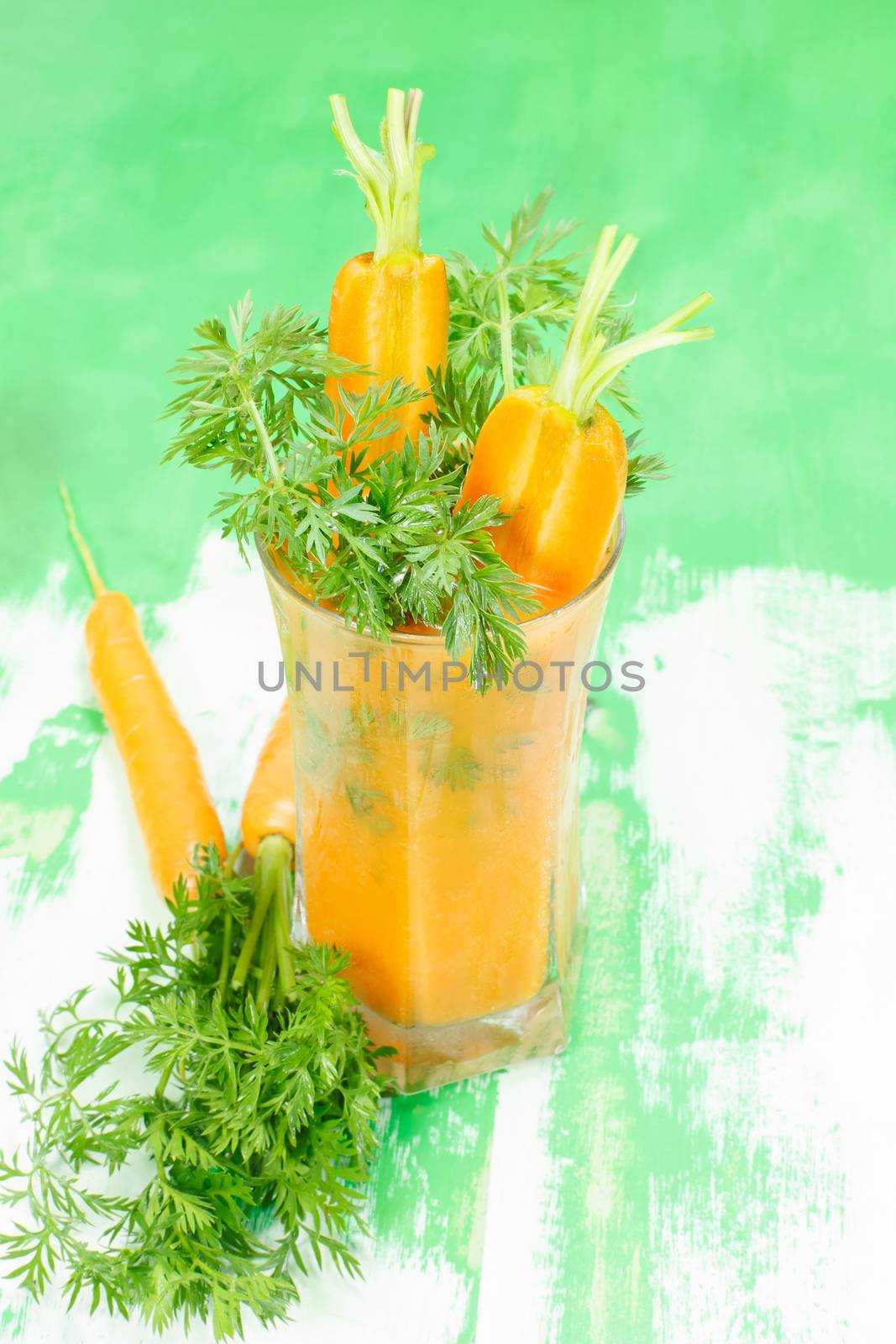Carrot juice in glass and vegetables beside