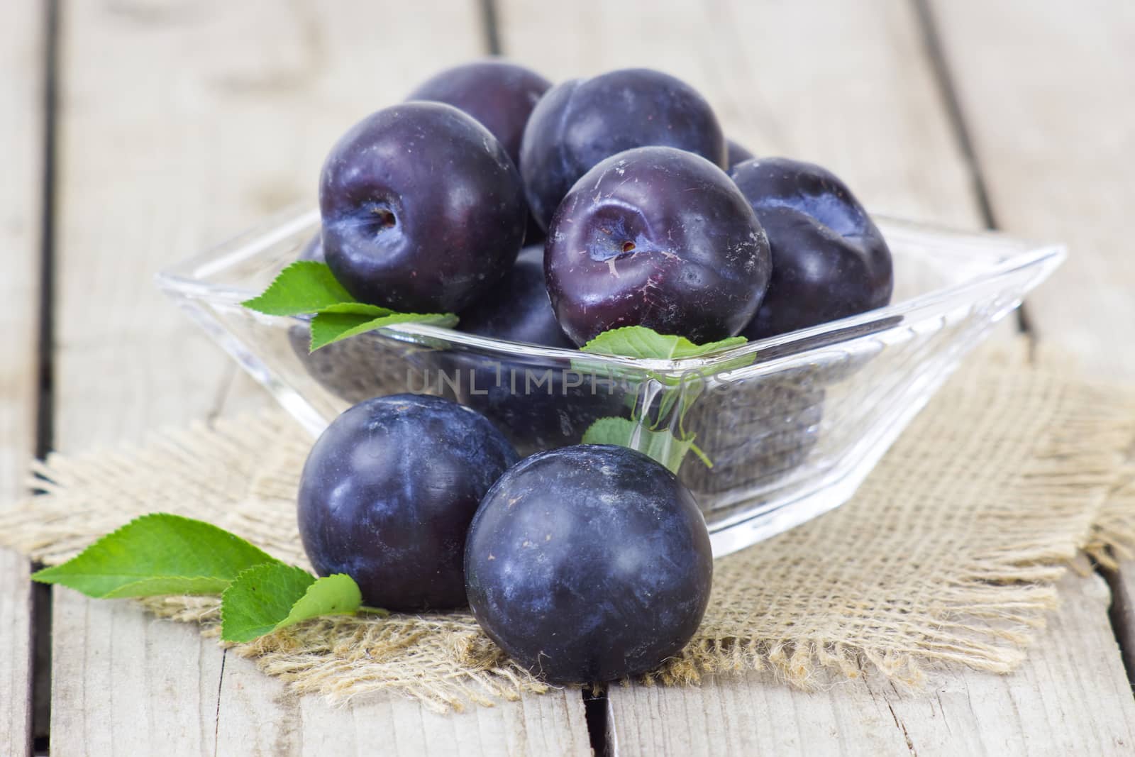 fresh plums in a bowl on old wooden background