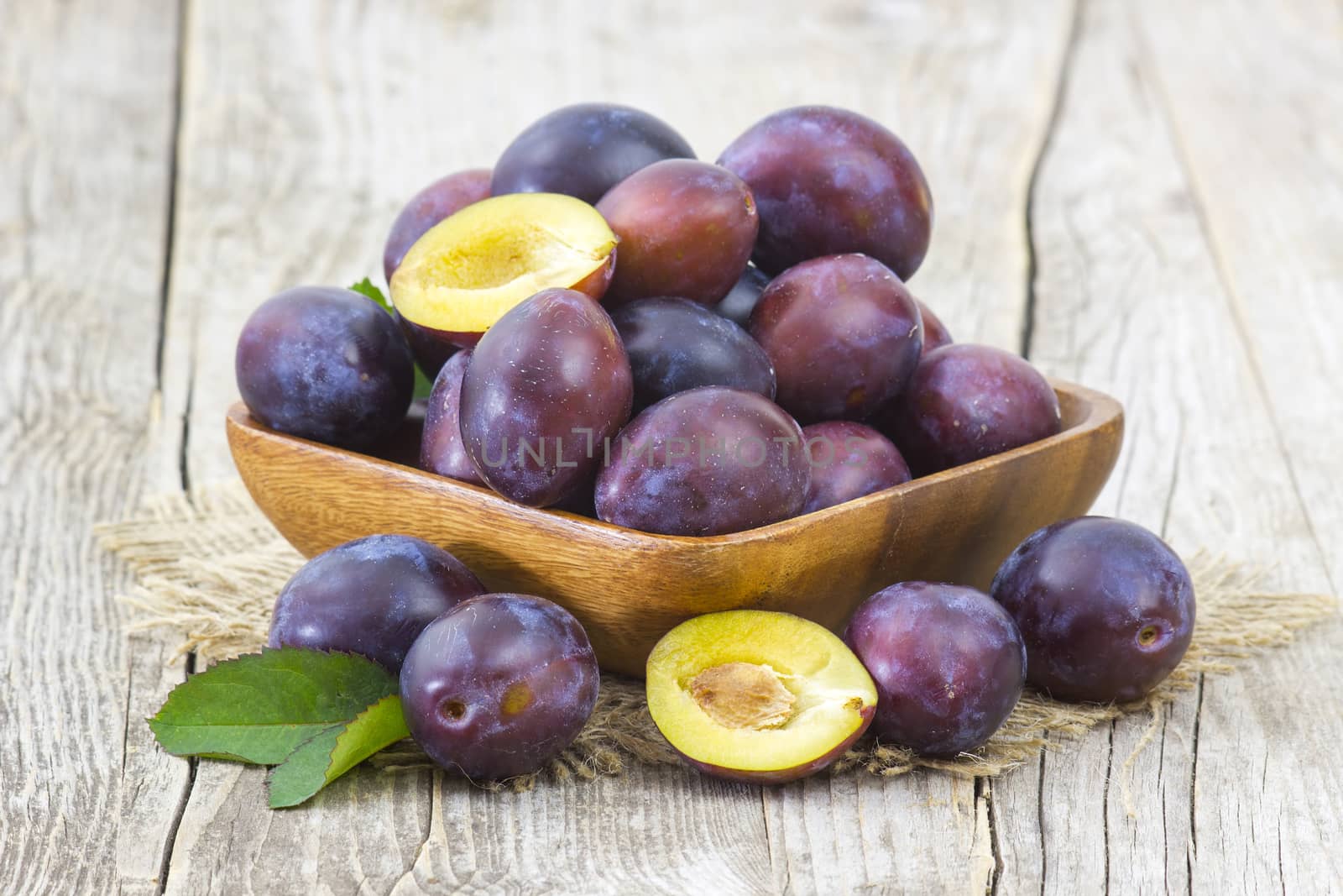 fresh plums in a bowl on old wooden background