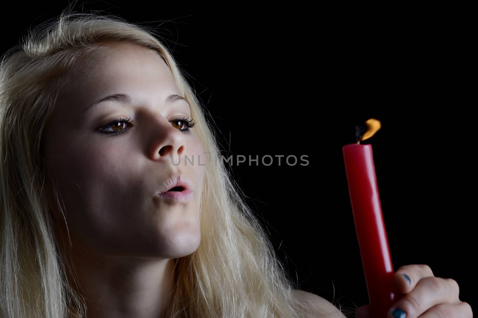 beautiful young blond woman blowing candle