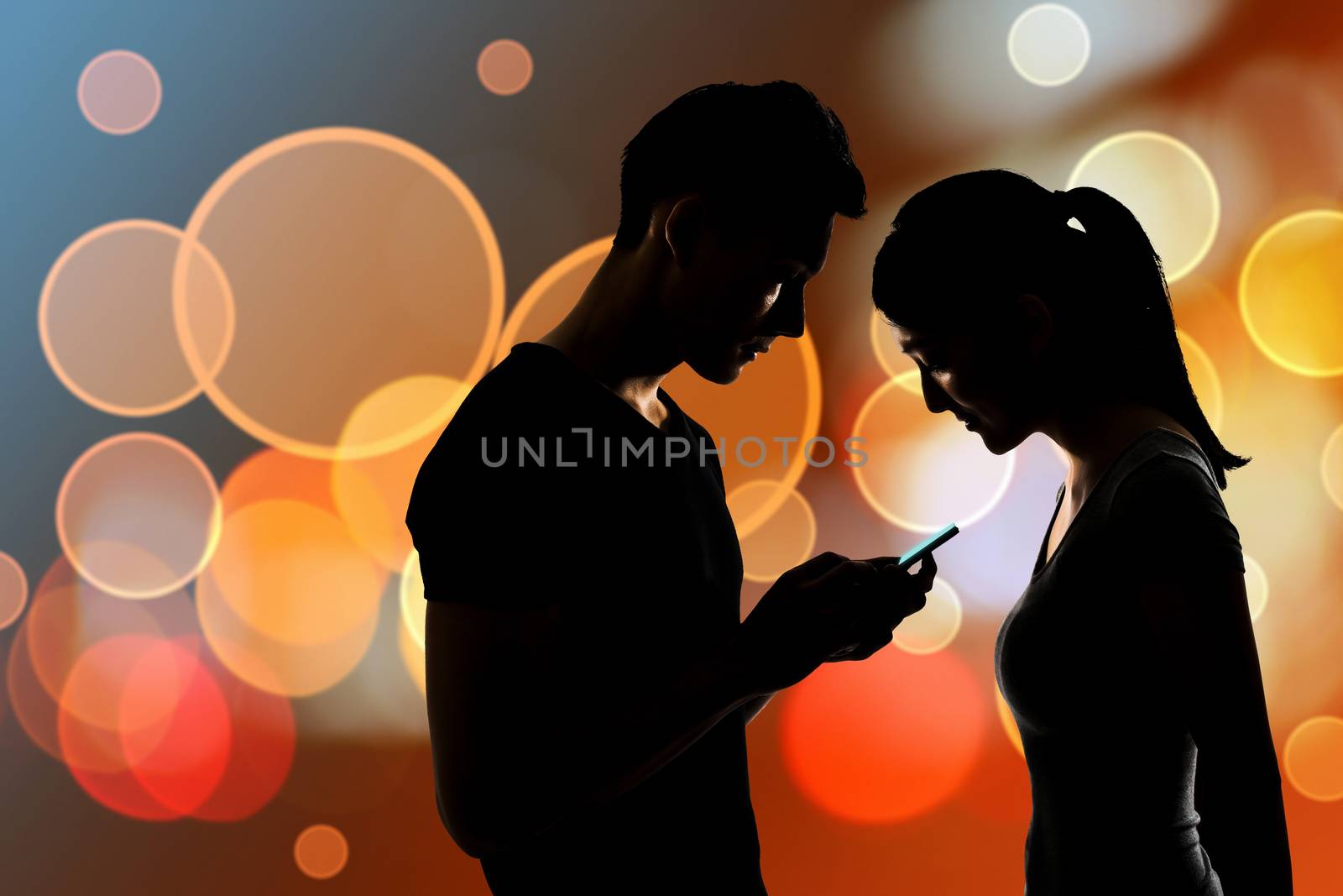 Couple using cellphone, silhouette portrait.