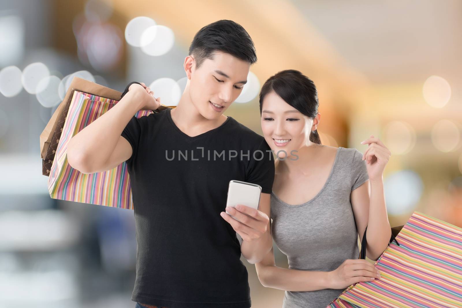 Young Asian couple shopping and looking at cellphone, closeup portrait.