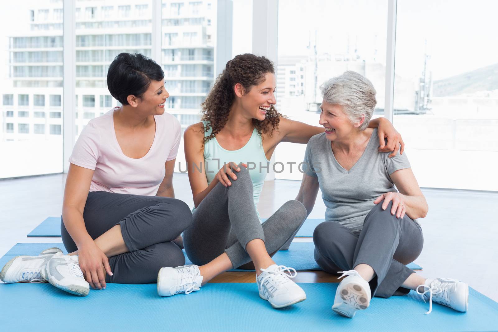 Full length of cheerful women sitting in the yoga class