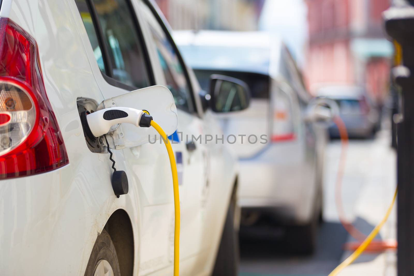 Power supply for electric car charging.  Electric car charging station. Close up of the power supply plugged into an electric car being charged.
