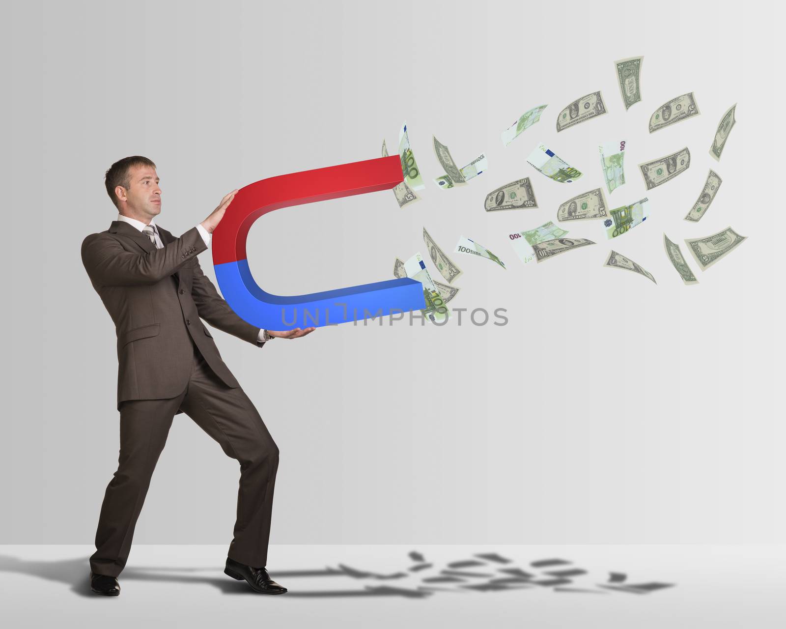 Businessman in suit holding big magnet and attracts money by cherezoff