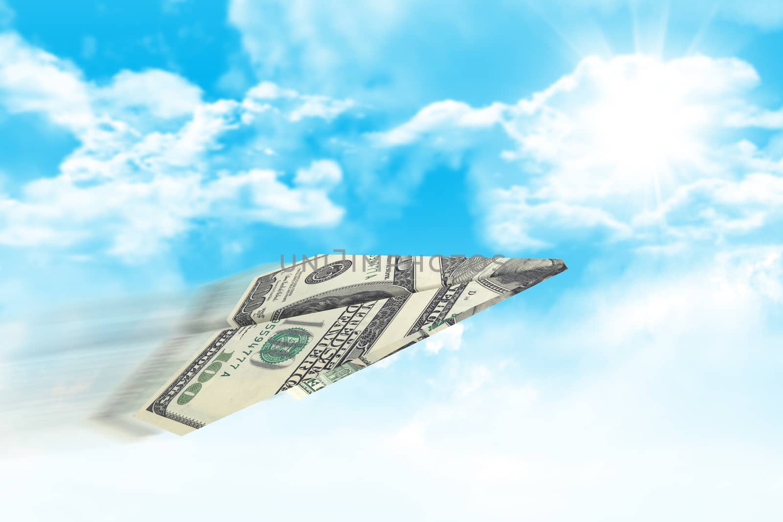 Paper airplane made of hundred dollar bill. Sky and clouds in the background