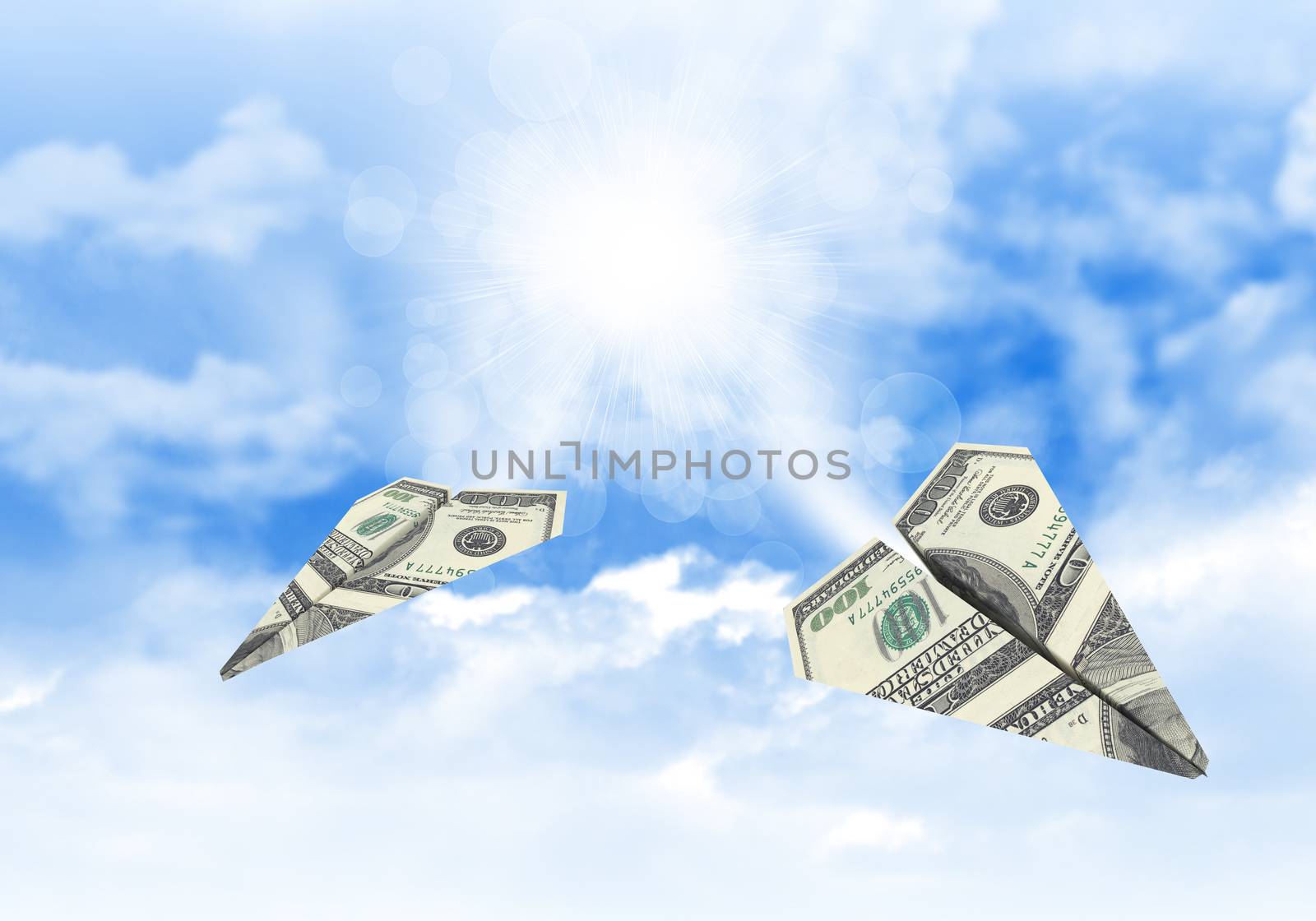 Paper airplanes made of hundred dollar bills. Sky and clouds in the background
