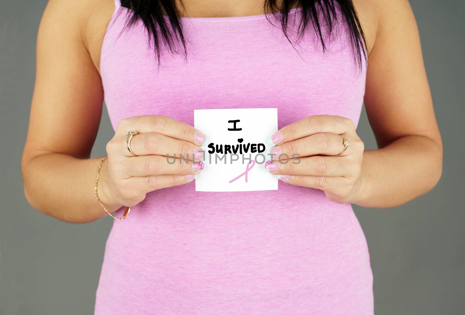 Woman in pink holding cancer survivor text with ribbon