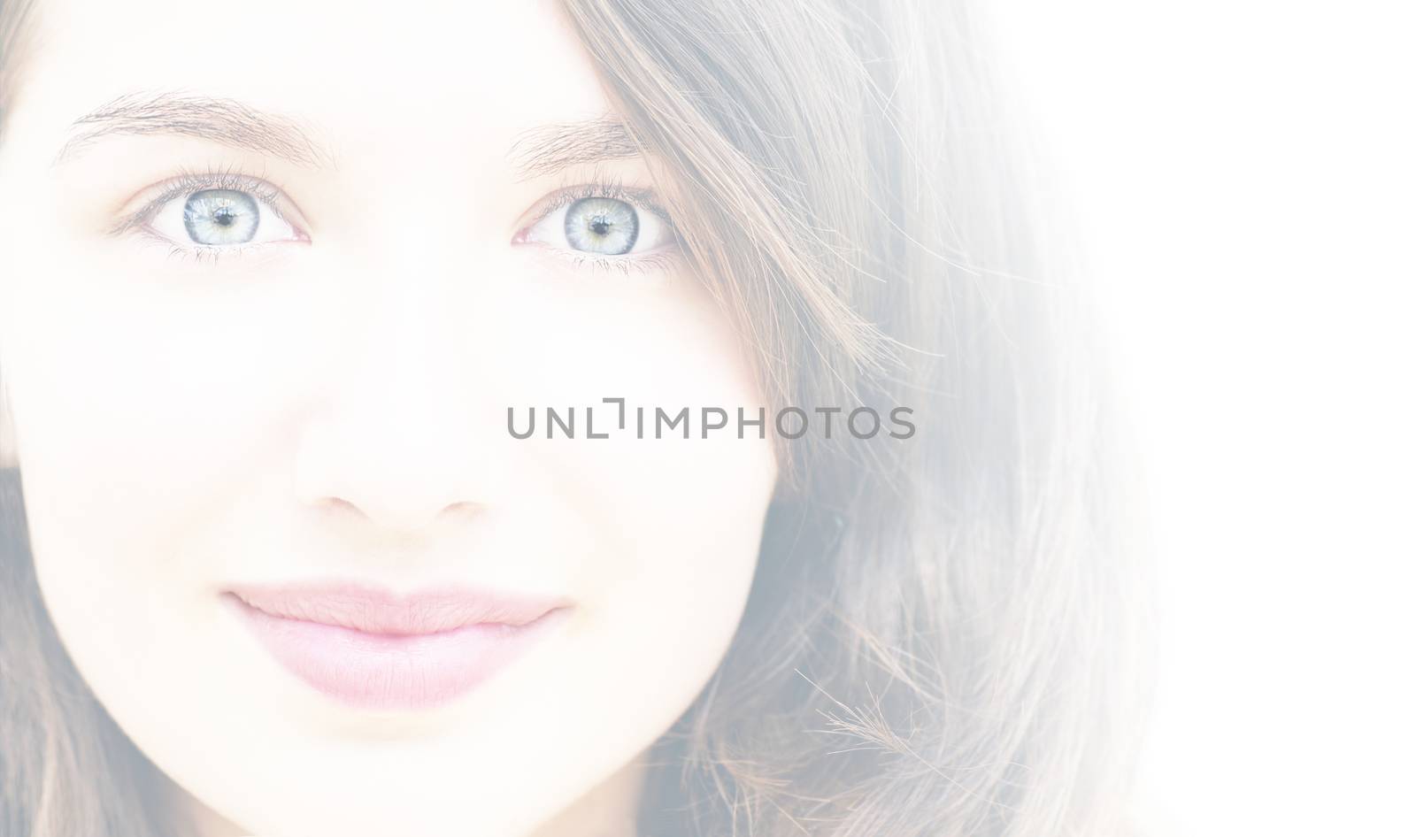 Portrait of a beautiful young woman, wide eyes and little smile, high key, white filter