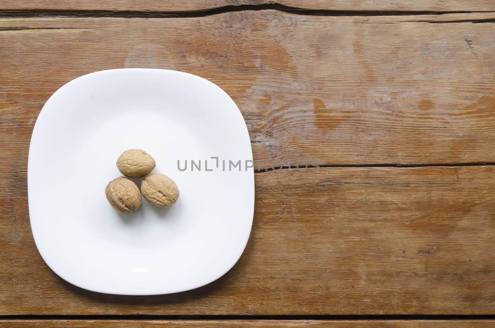 white ceramic dish with three walnuts on the vintage wooden table